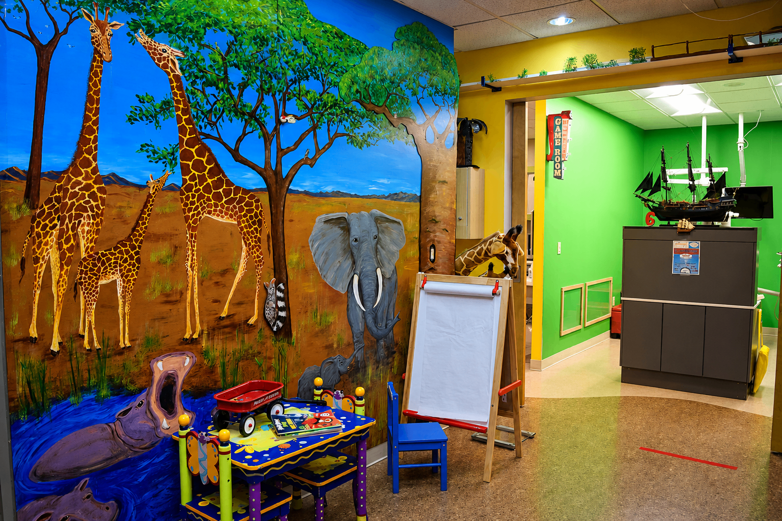 Hallway mural with giraffes, elephant, hippo, and kids play area