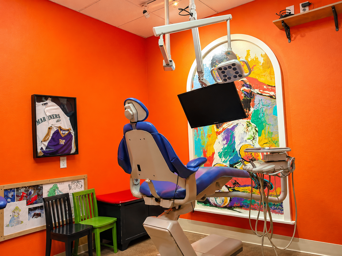 Orange treatment room with colorful artwork behind the dental chair