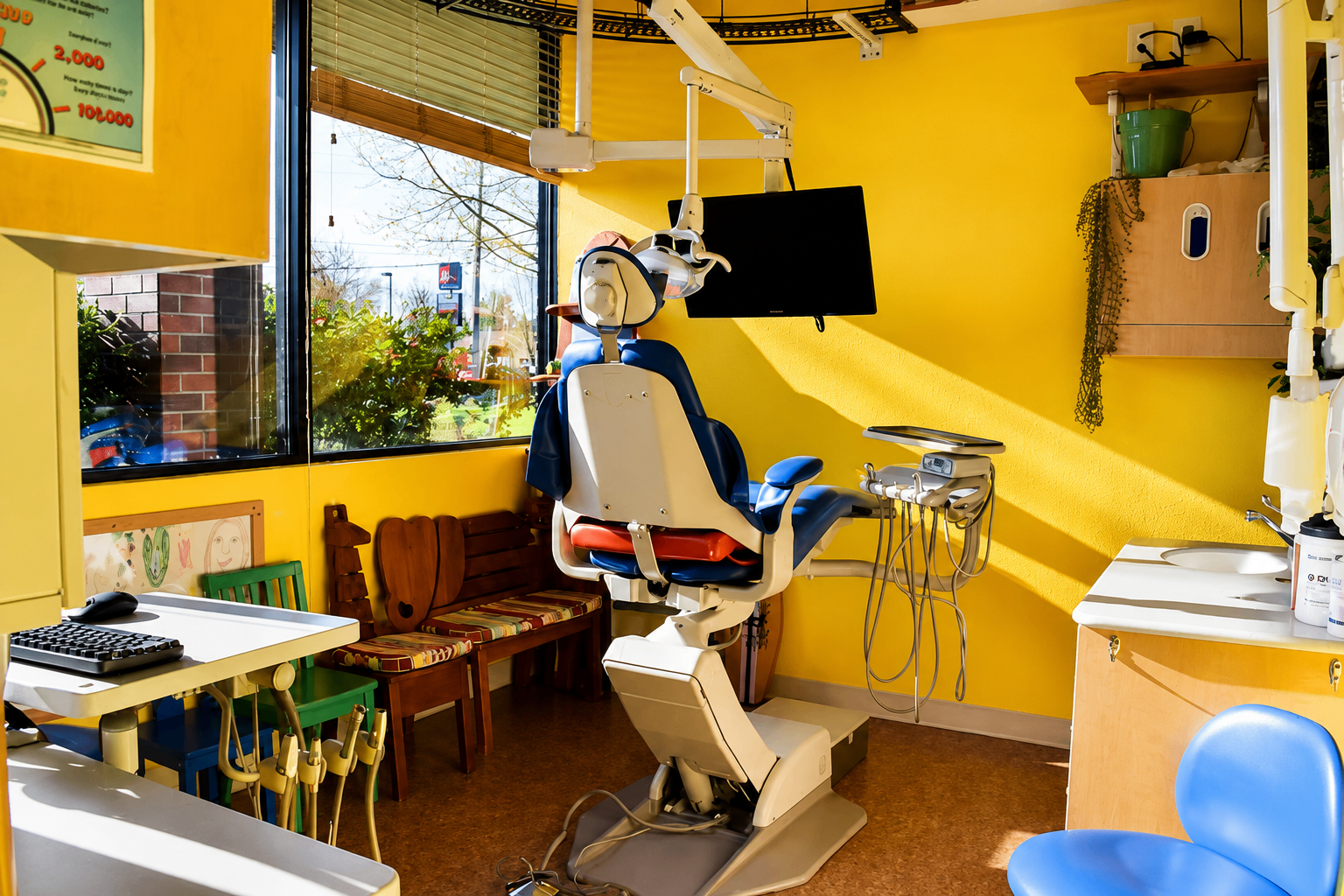 Sunny yellow treatment room with blue dental chair beside a large window